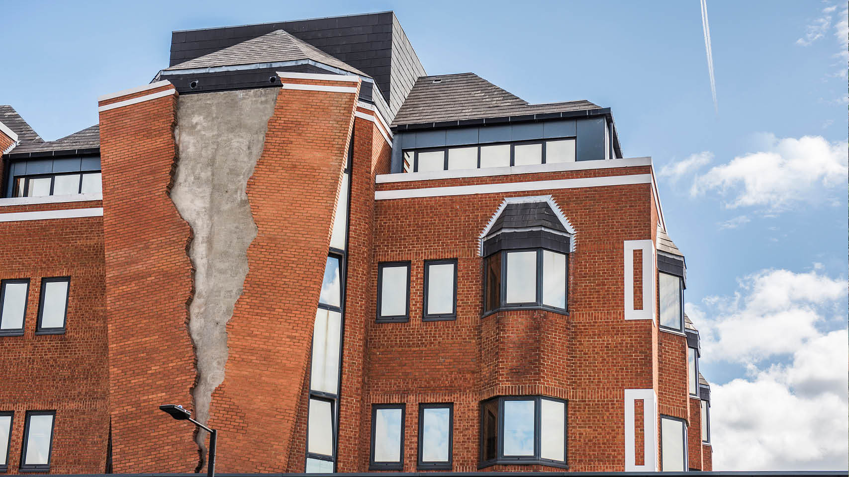 Skulptur von Alex Chinneck an der Fassade eines Ziegelsteinhauses