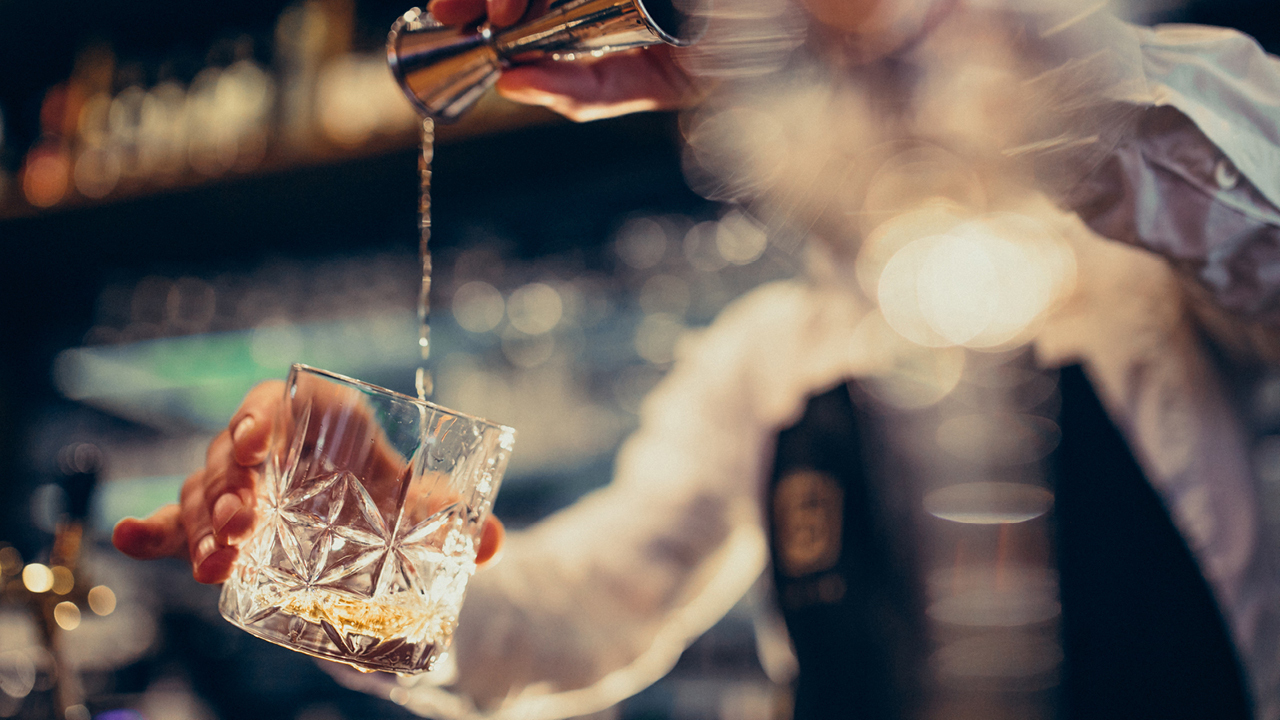 Bartender giesst Gin in ein Glas